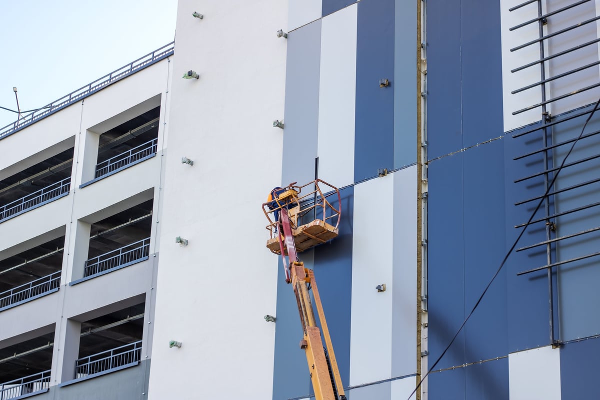 Worker in a lift painting the exterior facade of a commercial building