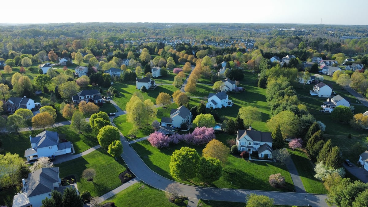 Aerial view of a residential suburban community with rooftops and tree-lined streets