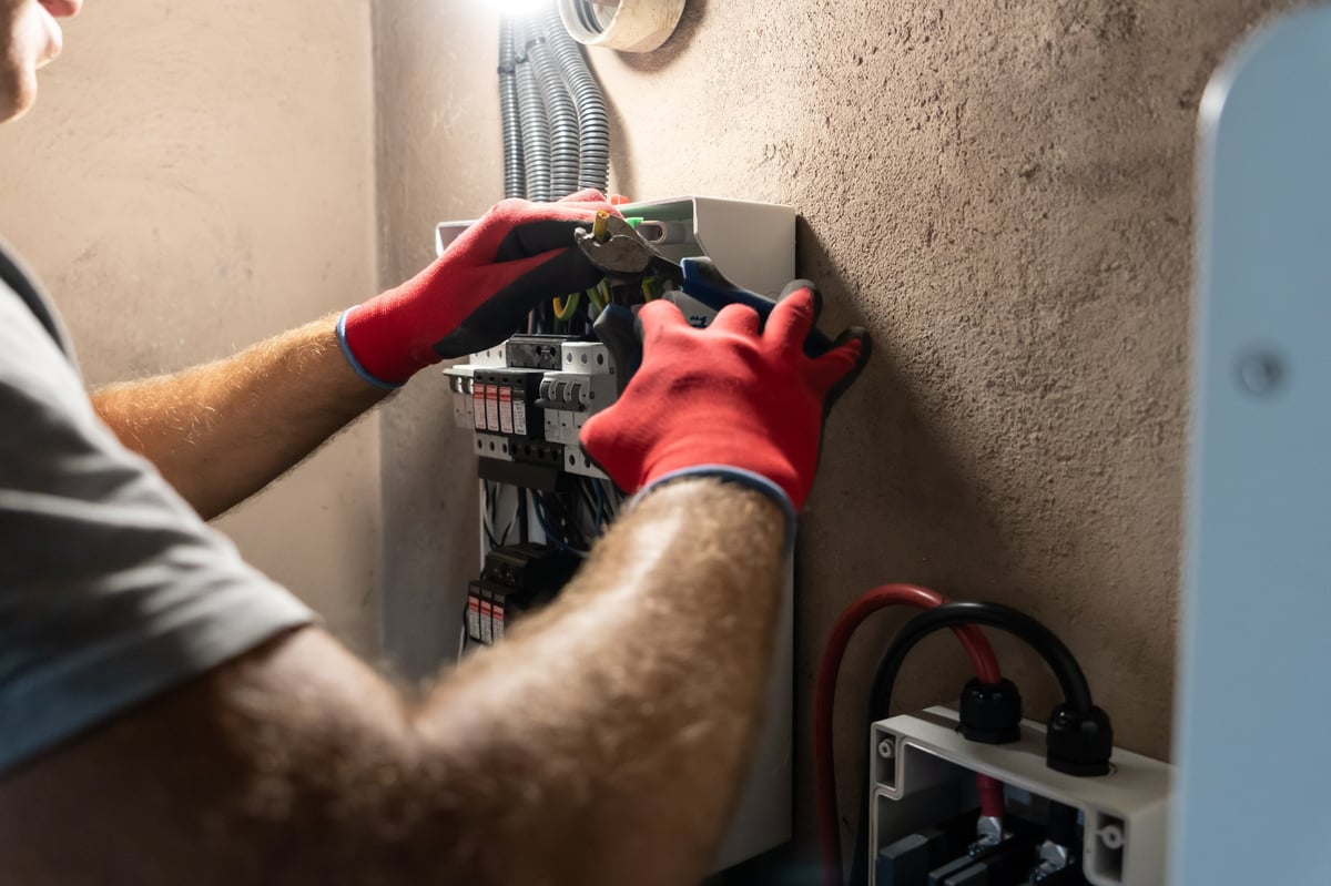 Electrician performing maintenance inside an electrical panel, ensuring safety and proper connection