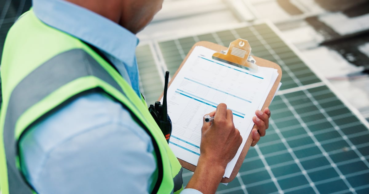 Technician reviewing a maintenance checklist on a clipboard while inspecting equipment on a rooftop